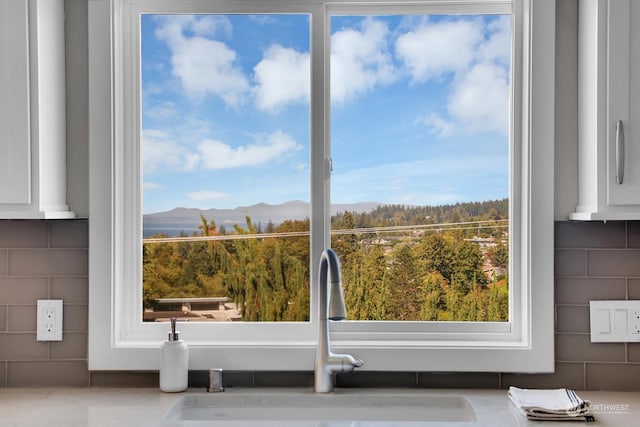 details with white cabinets, a mountain view, tasteful backsplash, and sink