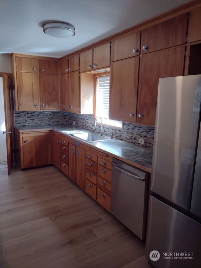 kitchen with backsplash, light hardwood / wood-style floors, appliances with stainless steel finishes, and sink