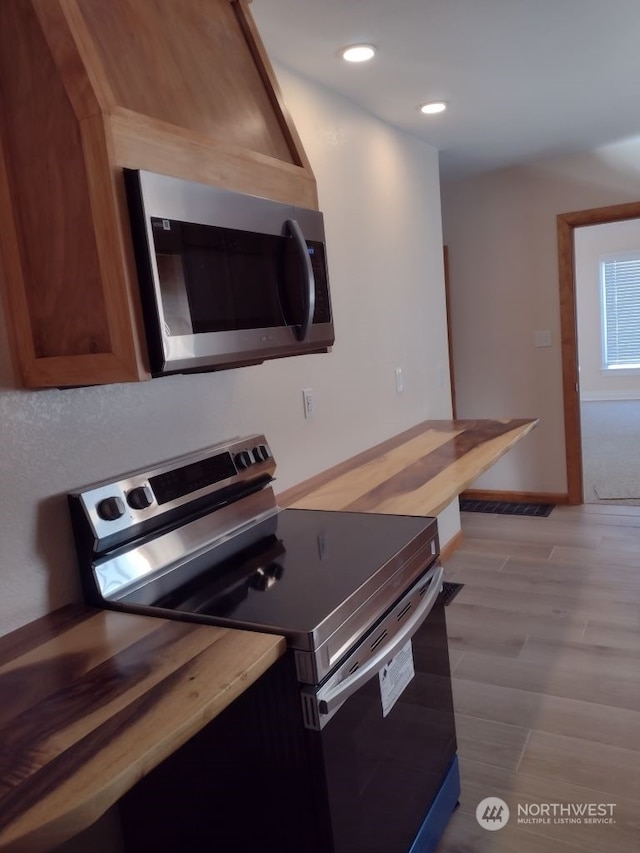 kitchen with butcher block countertops, appliances with stainless steel finishes, and light wood-type flooring