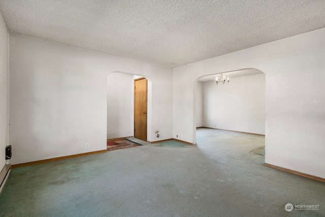 carpeted empty room featuring a textured ceiling and a notable chandelier