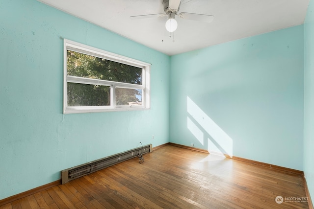 spare room with ceiling fan, baseboard heating, and hardwood / wood-style flooring