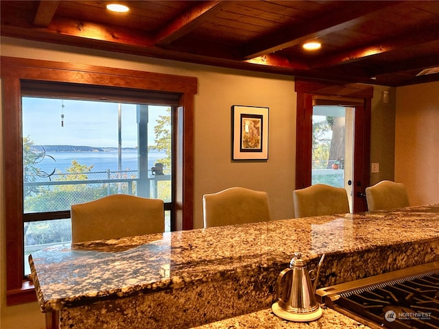 dining room featuring a water view, beamed ceiling, and wooden ceiling