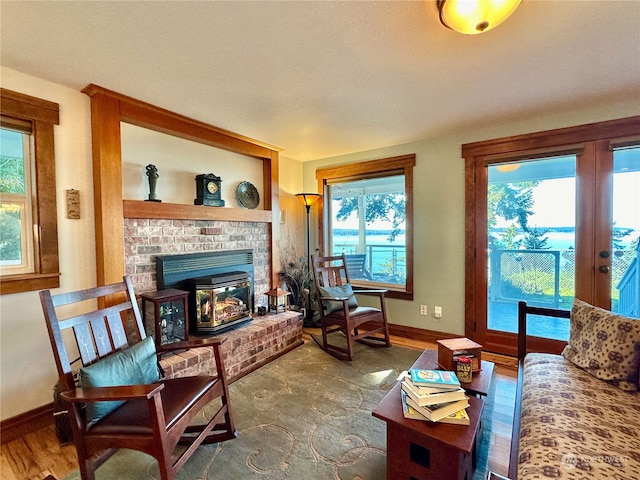 living room with hardwood / wood-style flooring, a brick fireplace, and a wealth of natural light