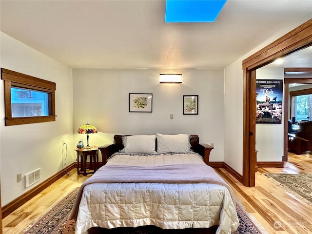bedroom featuring light wood finished floors, visible vents, and baseboards