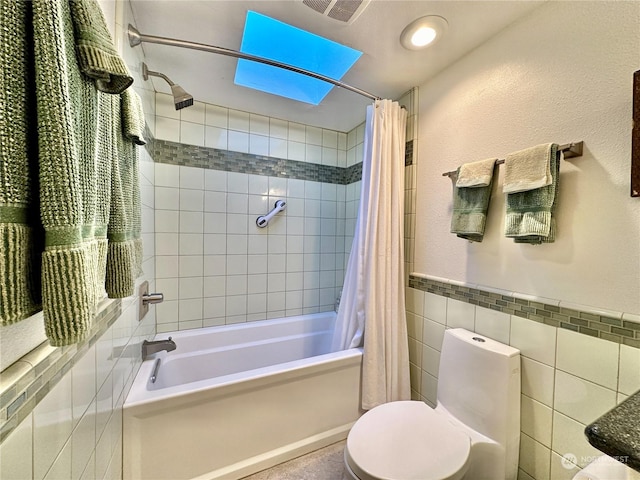 full bath with toilet, shower / bathtub combination with curtain, visible vents, wainscoting, and tile walls