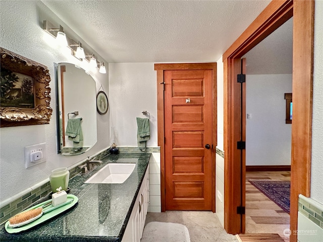 bathroom with wood-type flooring, backsplash, a textured ceiling, and vanity