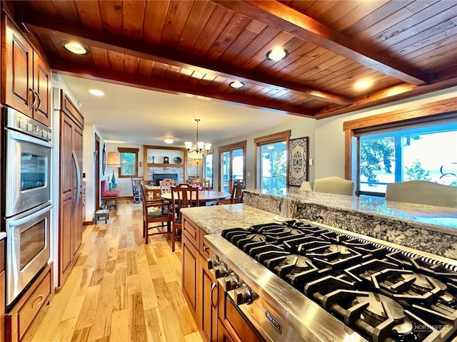 kitchen featuring cooktop, light wood finished floors, double oven, and beamed ceiling