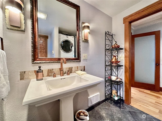 bathroom featuring visible vents, stacked washer / dryer, wood finished floors, a sink, and baseboards