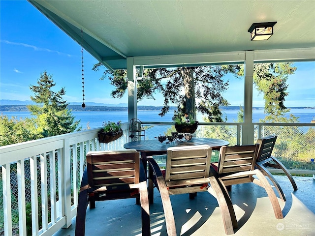 balcony with a water view and outdoor dining area