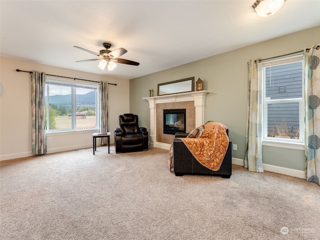 carpeted living room with ceiling fan and a tile fireplace