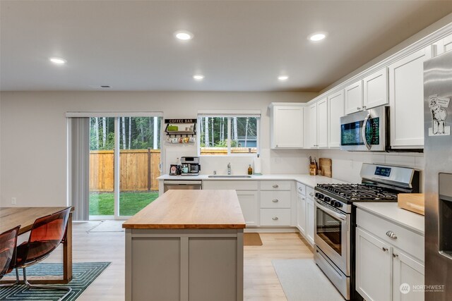 kitchen featuring butcher block counters, stainless steel appliances, a wealth of natural light, and a kitchen island