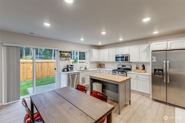 kitchen featuring white cabinets, butcher block counters, stainless steel appliances, light hardwood / wood-style flooring, and sink