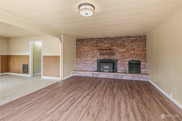 unfurnished living room featuring wood walls, hardwood / wood-style floors, and a large fireplace