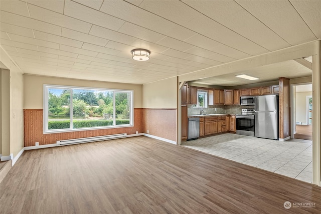 interior space featuring a baseboard radiator, light wood-type flooring, wood walls, and sink