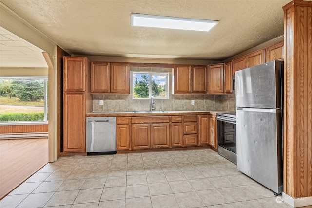 kitchen featuring light tile patterned floors, sink, a baseboard heating unit, stainless steel appliances, and decorative backsplash