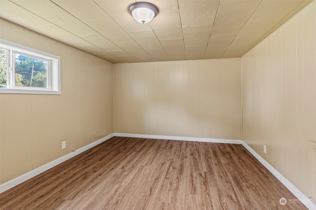 spare room featuring wood walls and hardwood / wood-style floors