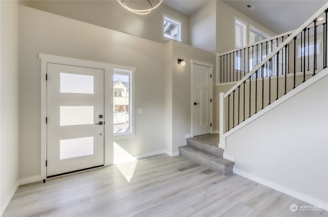 foyer with light wood-type flooring, a healthy amount of sunlight, and a high ceiling