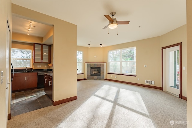 carpeted living room featuring ceiling fan, track lighting, sink, and a tile fireplace