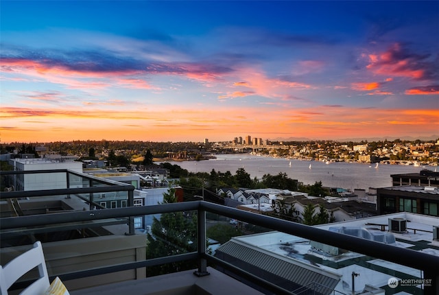 balcony at dusk featuring a water view