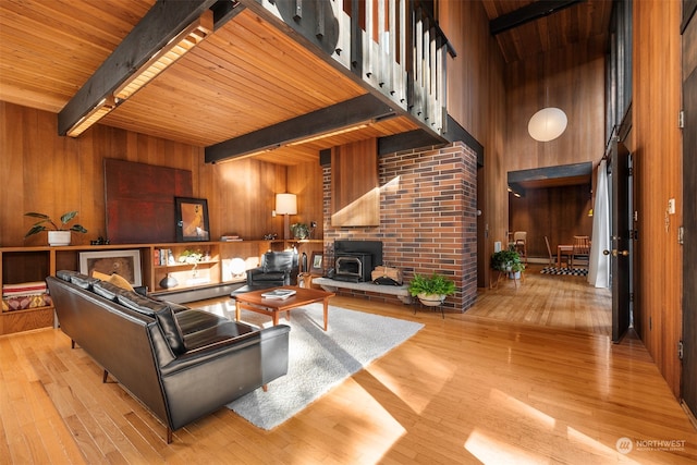 living room with wooden ceiling, light hardwood / wood-style floors, beamed ceiling, and a wood stove