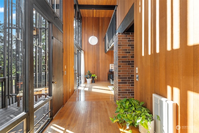 foyer with wood ceiling, wooden walls, a high ceiling, and hardwood / wood-style flooring