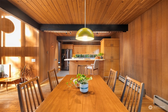 dining area with wood walls, light hardwood / wood-style floors, beam ceiling, and a baseboard radiator