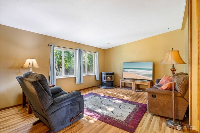 living room with lofted ceiling, light hardwood / wood-style floors, and a wood stove