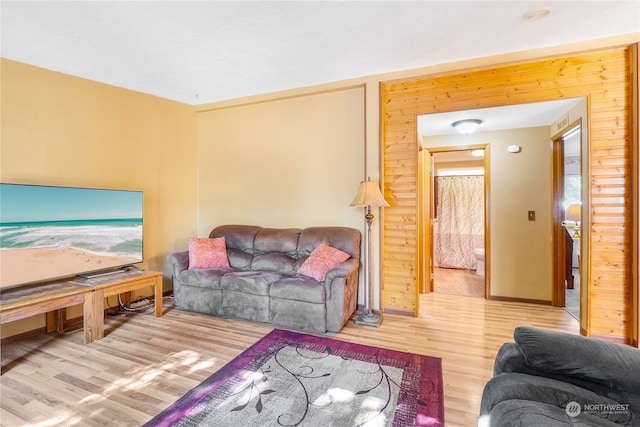 living room featuring light wood-type flooring and wood walls