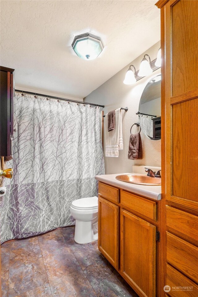 bathroom featuring vanity, toilet, and a textured ceiling