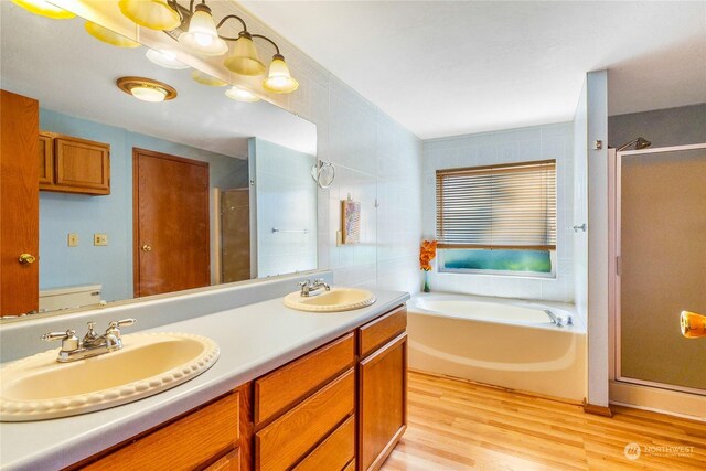 bathroom with independent shower and bath, vanity, and hardwood / wood-style floors