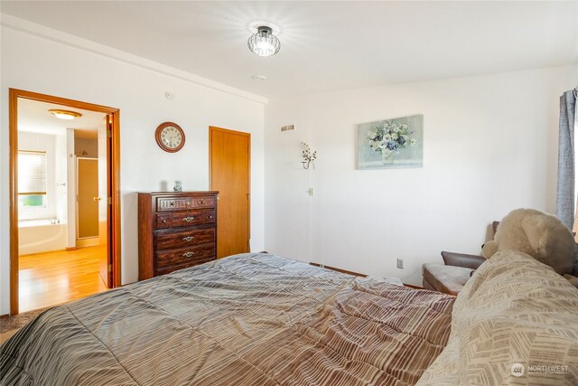 bedroom featuring ensuite bath and hardwood / wood-style flooring