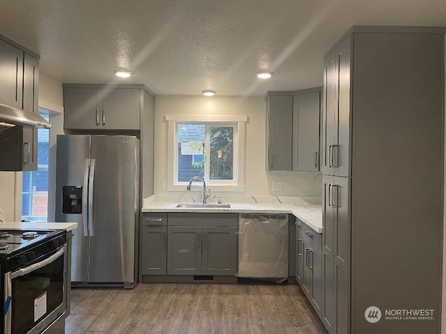 kitchen with gray cabinets, a textured ceiling, dark hardwood / wood-style floors, sink, and stainless steel appliances