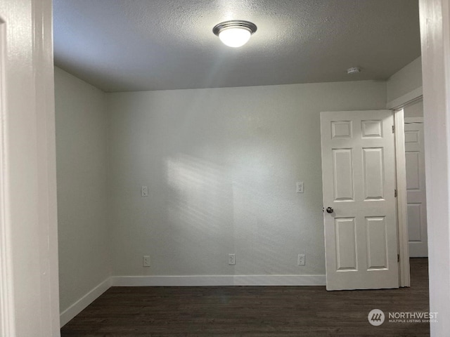 unfurnished room featuring a textured ceiling and dark wood-type flooring