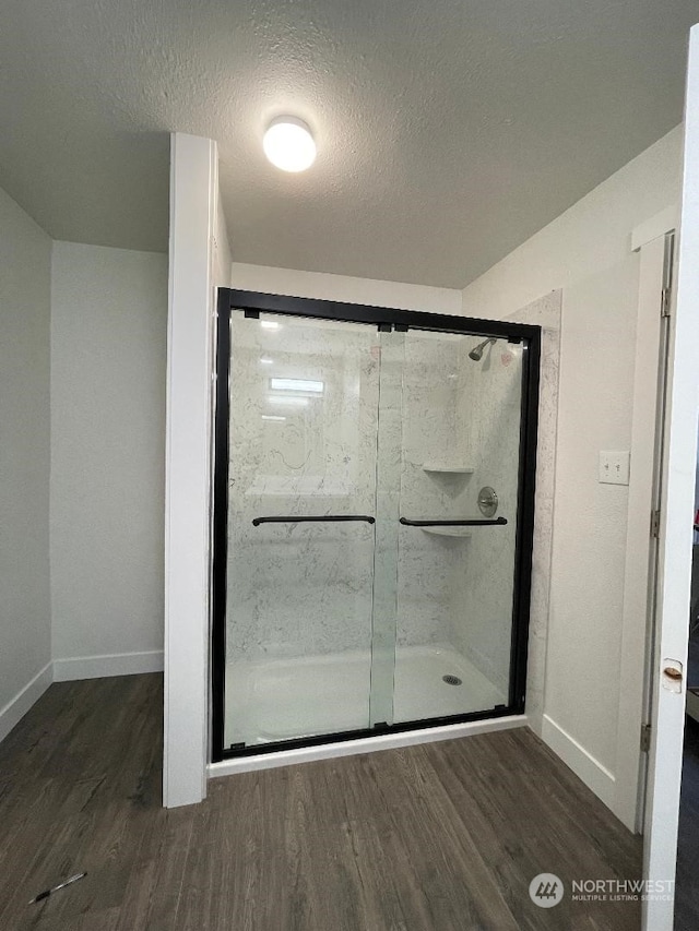 bathroom with wood-type flooring, a textured ceiling, and a shower with shower door