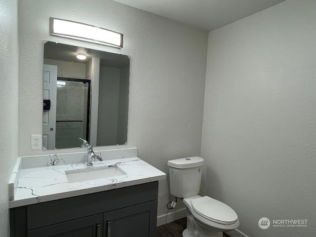 bathroom with an enclosed shower, hardwood / wood-style flooring, vanity, and toilet