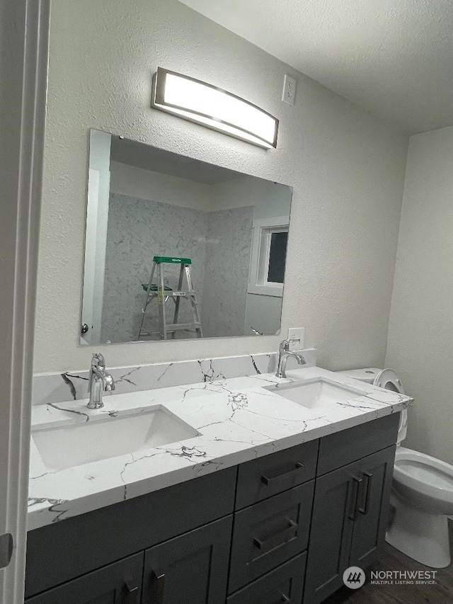 bathroom featuring a textured ceiling, vanity, and toilet