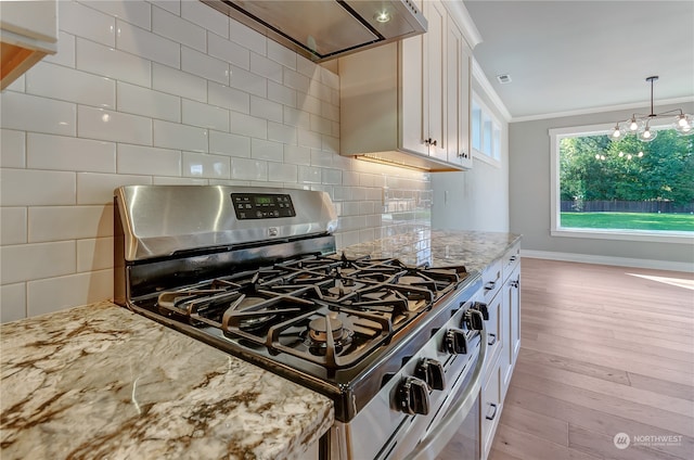 kitchen featuring light stone counters, ornamental molding, white cabinetry, stainless steel gas range oven, and light hardwood / wood-style floors