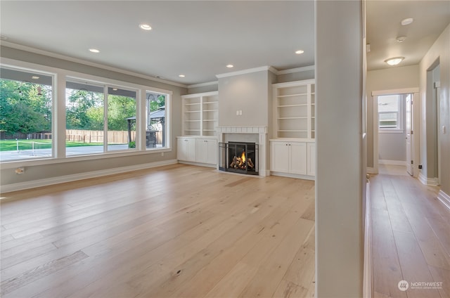 unfurnished living room with built in shelves, light hardwood / wood-style flooring, and crown molding