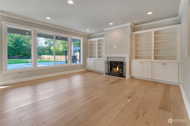 unfurnished living room with light wood-type flooring, built in shelves, and crown molding