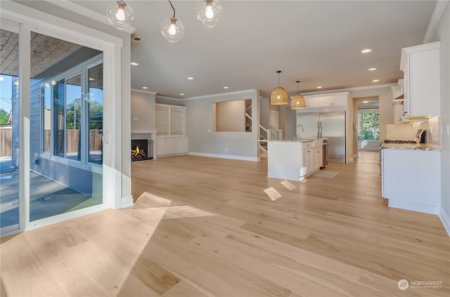 kitchen featuring light hardwood / wood-style flooring, white cabinets, hanging light fixtures, and crown molding