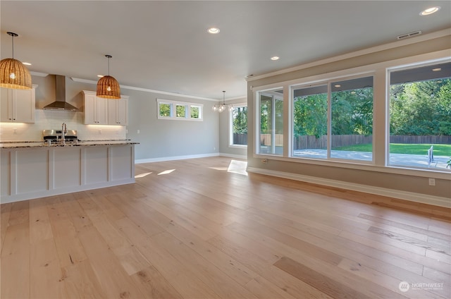 unfurnished living room featuring light wood-type flooring, a chandelier, and a healthy amount of sunlight