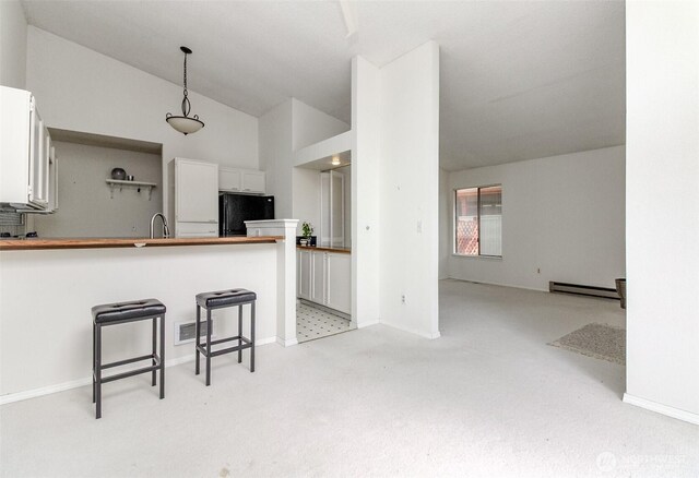 31717 48th Ln SW Unit A, Federal Way, WA 98023 - kitchen with freestanding refrigerator, light carpet, white cabinets, a baseboard radiator, and a breakfast bar area