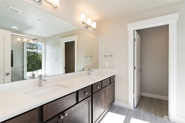 bathroom featuring a shower with door and vanity