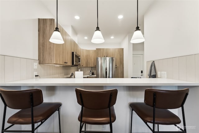 kitchen with pendant lighting, stainless steel appliances, kitchen peninsula, and a breakfast bar