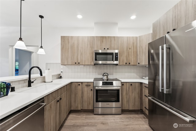 kitchen featuring light wood-type flooring, sink, appliances with stainless steel finishes, decorative light fixtures, and backsplash