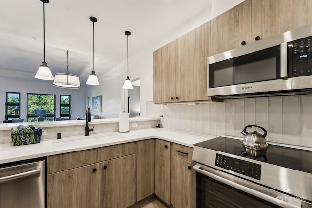 kitchen with pendant lighting, stainless steel appliances, sink, and tasteful backsplash