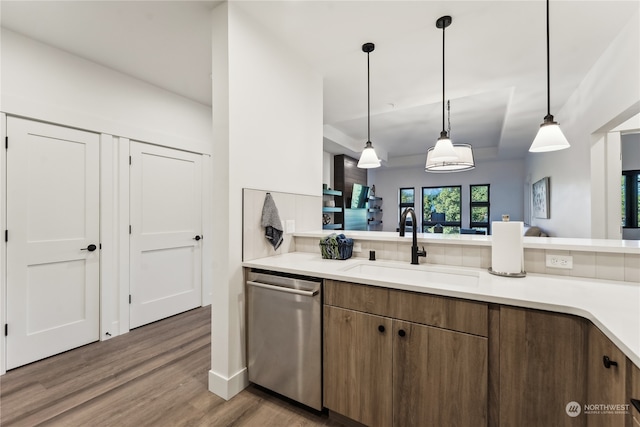 kitchen featuring sink, tasteful backsplash, decorative light fixtures, dishwasher, and hardwood / wood-style flooring