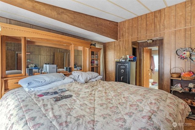 bedroom featuring wood walls and ensuite bath