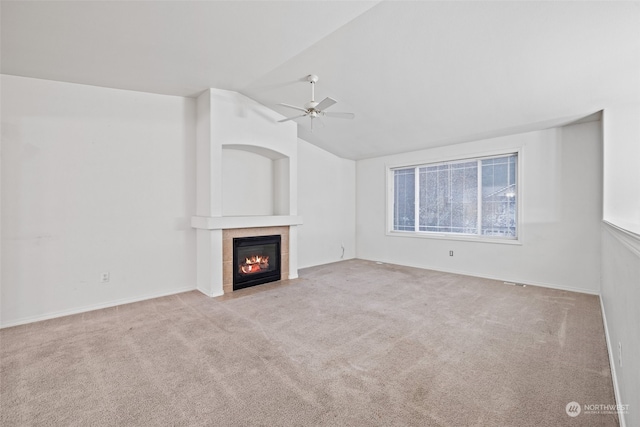 unfurnished living room featuring a tile fireplace, vaulted ceiling, ceiling fan, and light colored carpet