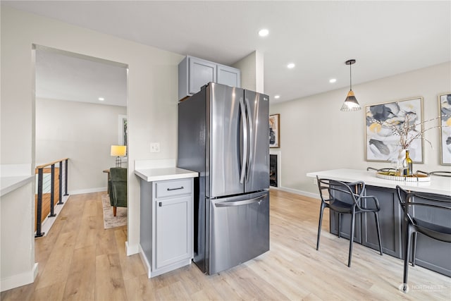 kitchen with a kitchen breakfast bar, stainless steel fridge, light hardwood / wood-style floors, pendant lighting, and gray cabinets